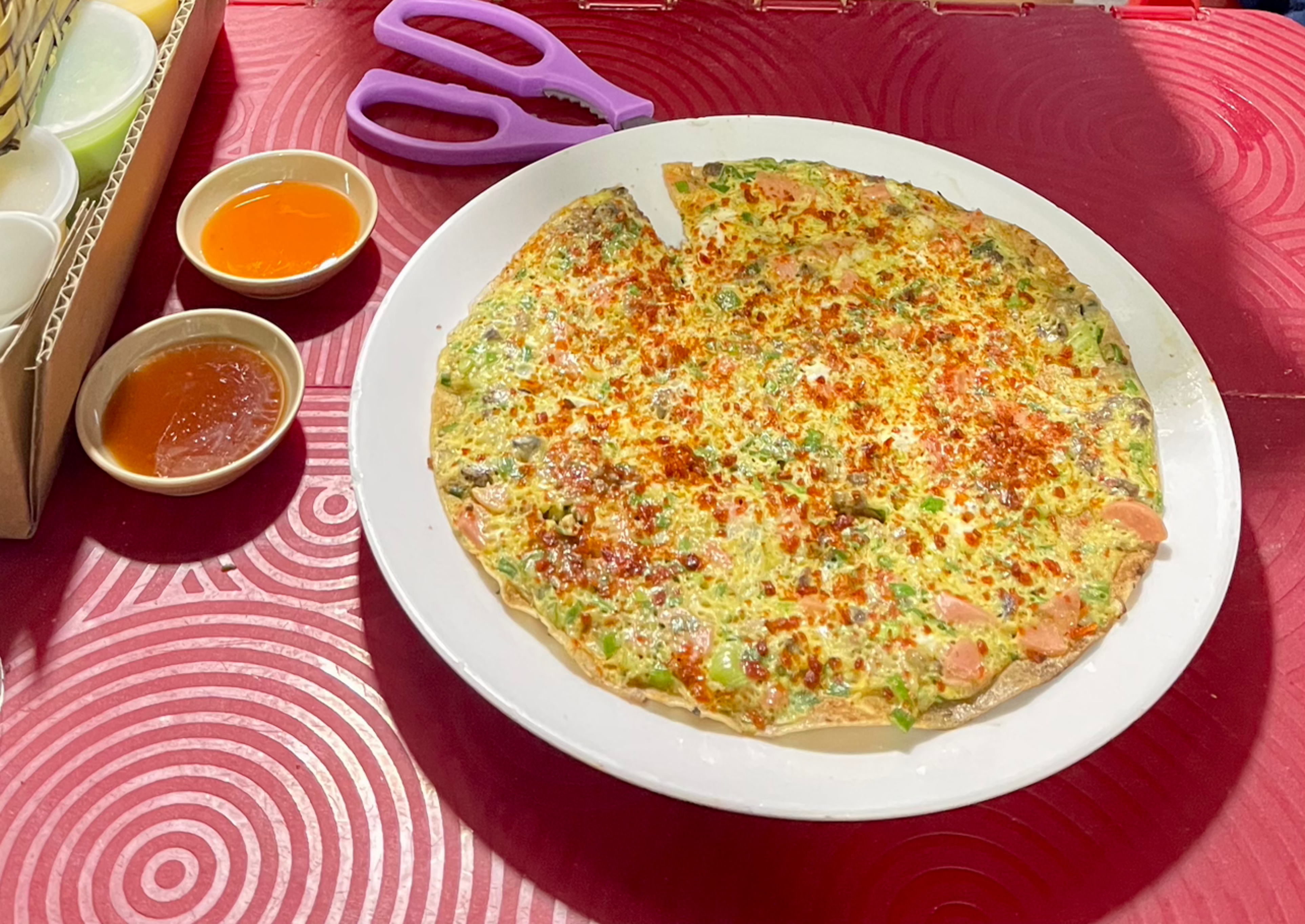 Tay người nướng đang phết trứng lên bánh tráng